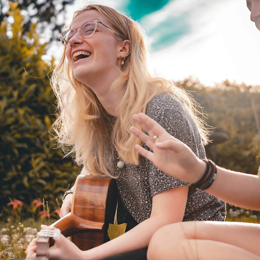 woman smiling playing guitar