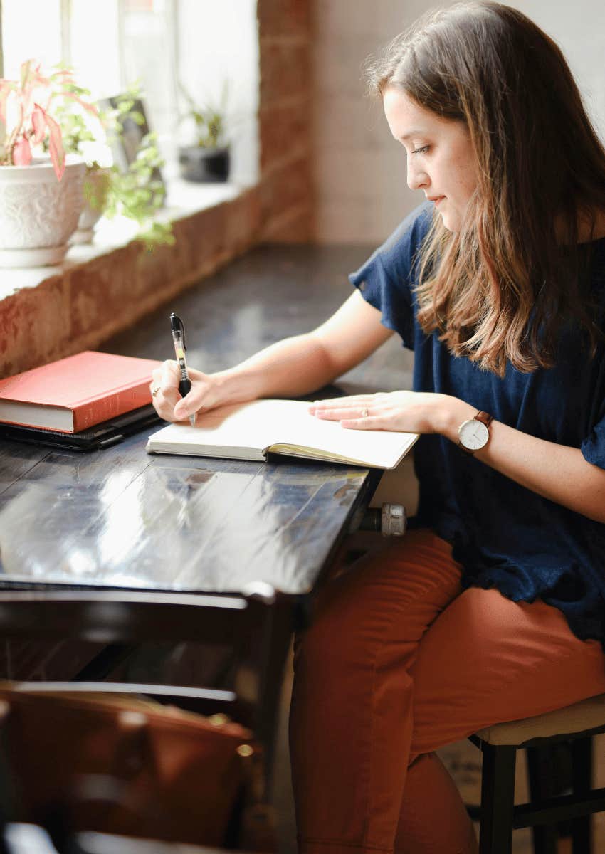 woman journaling next to window