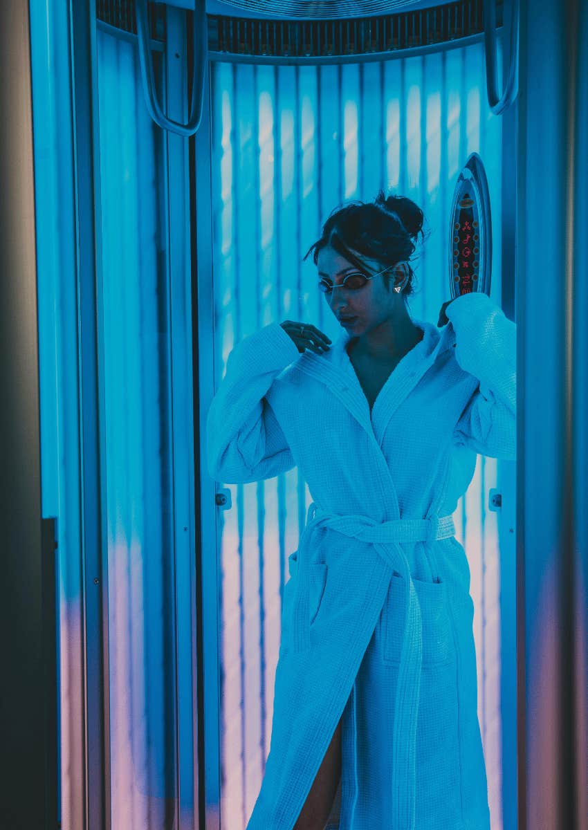 woman in a robe standing in a tanning room