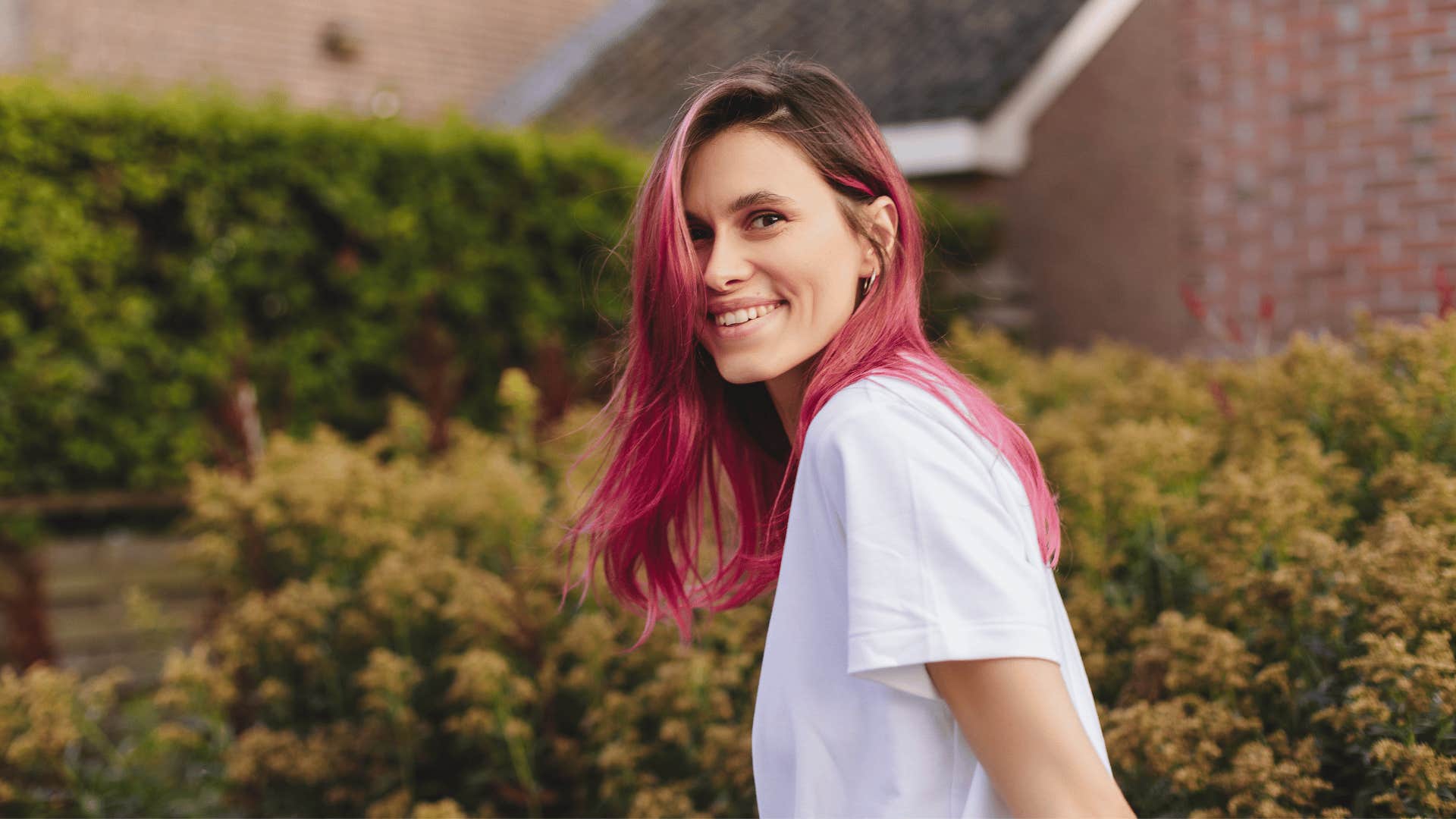 quirky woman with pink hair smiling outside