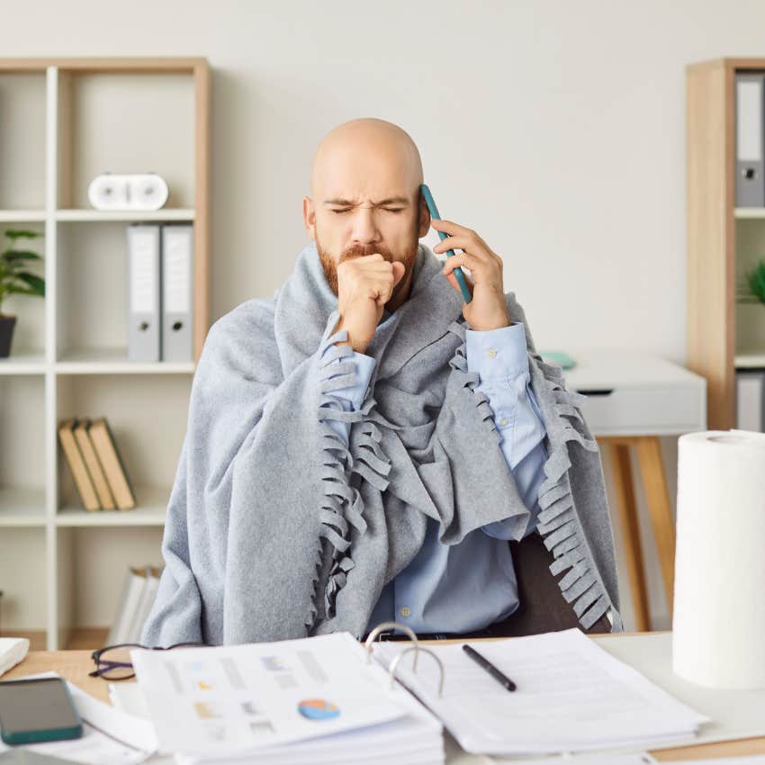 sick employee talking on phone and working at desk