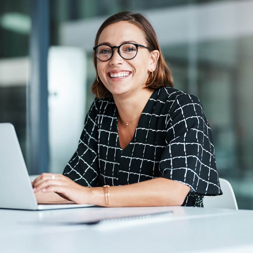 happy female employee sitting at desk in front of laptop