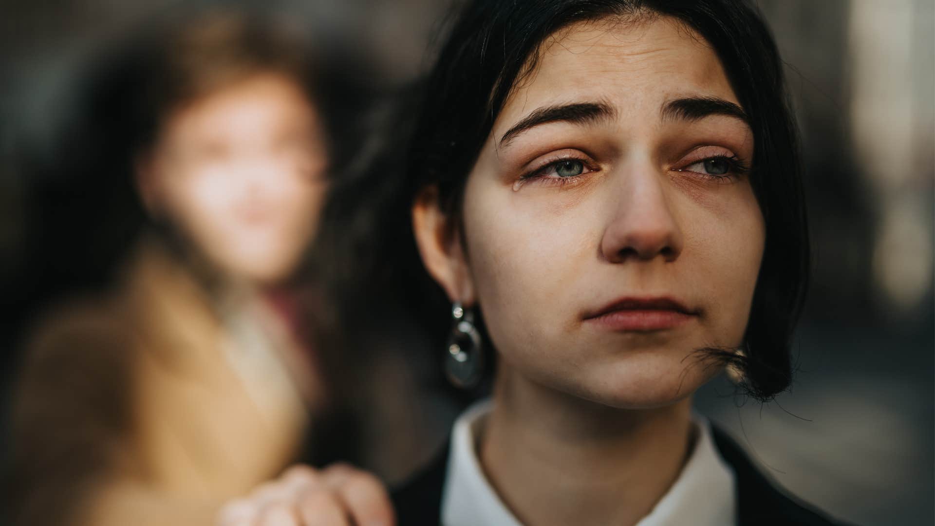 sad crying woman saying I'm used to it while friend touches her shoulder