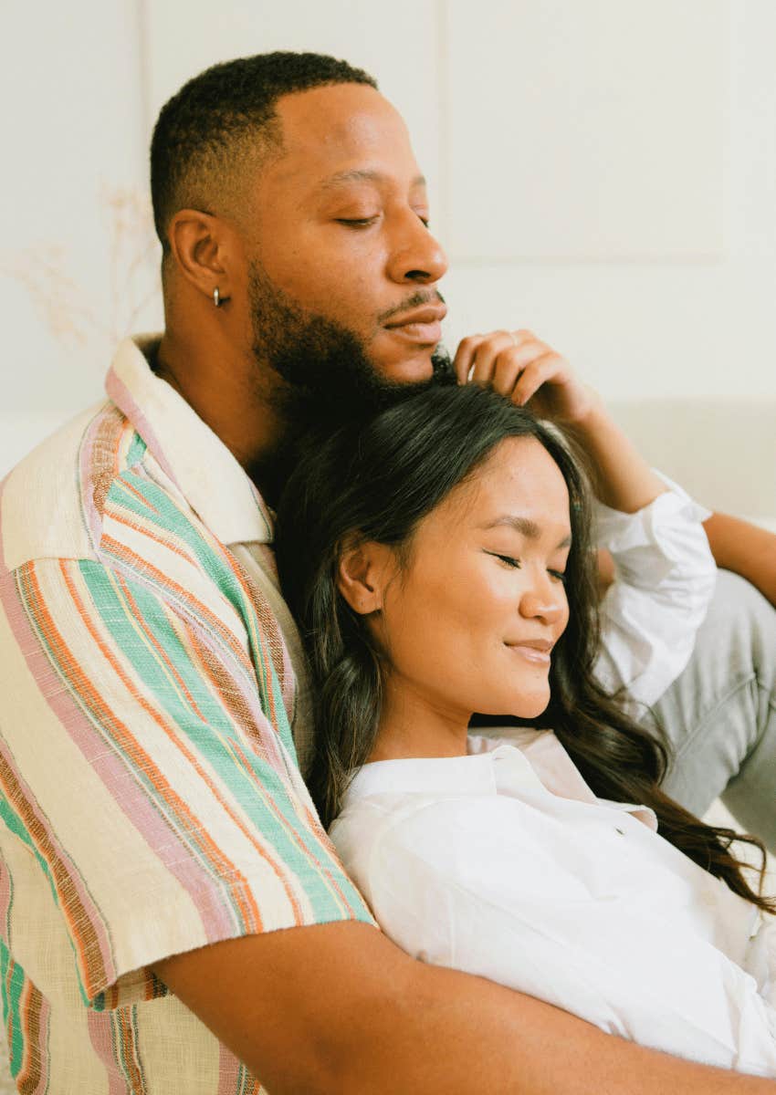 young couple sitting close on couch practicing forgiveness