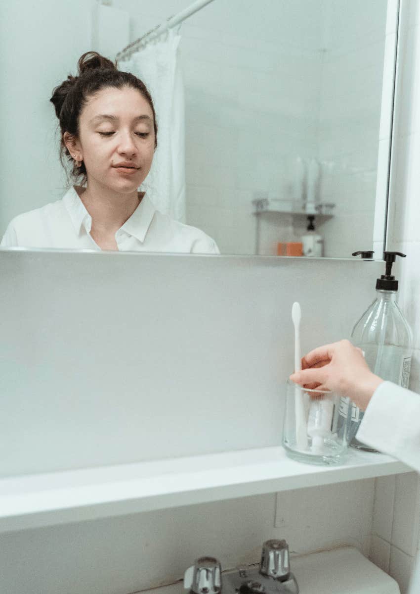 young woman standing in her bathroom alone