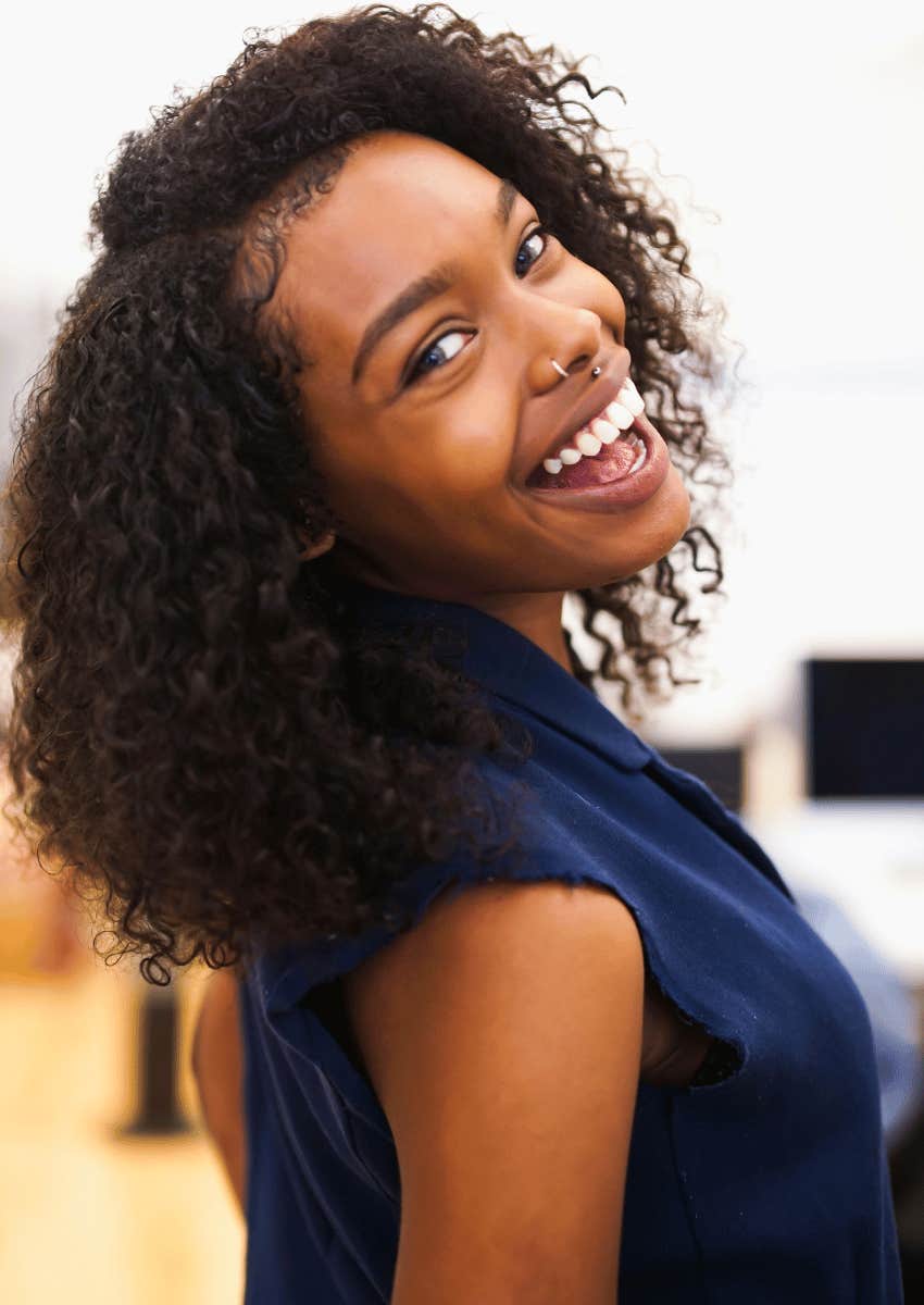 young woman smiling over her shoulder being fully present