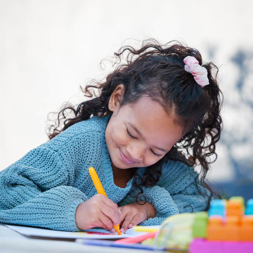 little girl drawing stars and moons on paper