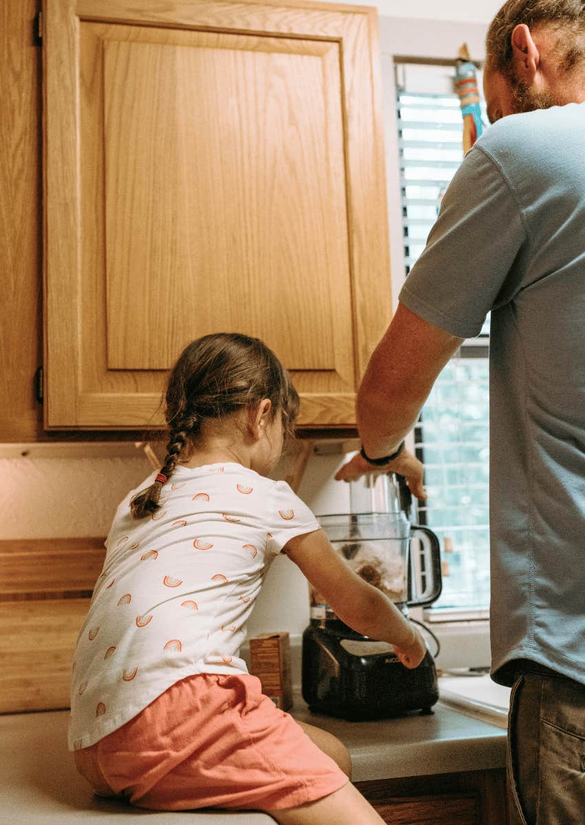 child helping man with blender in kitchen