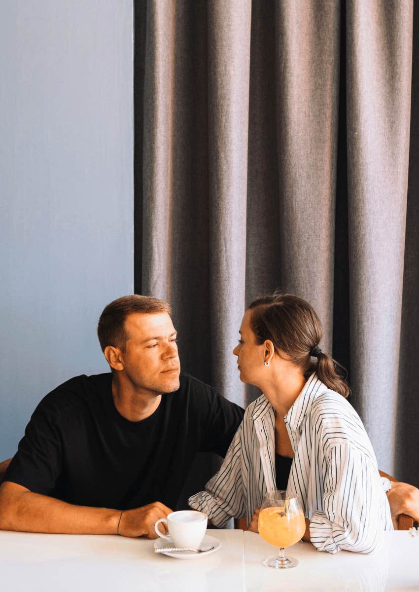 couple sitting close at a dining table talking