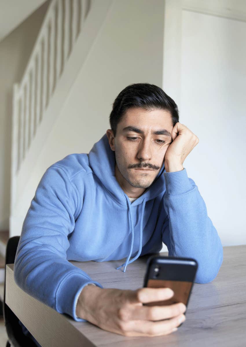 despondent man looking down at his phone
