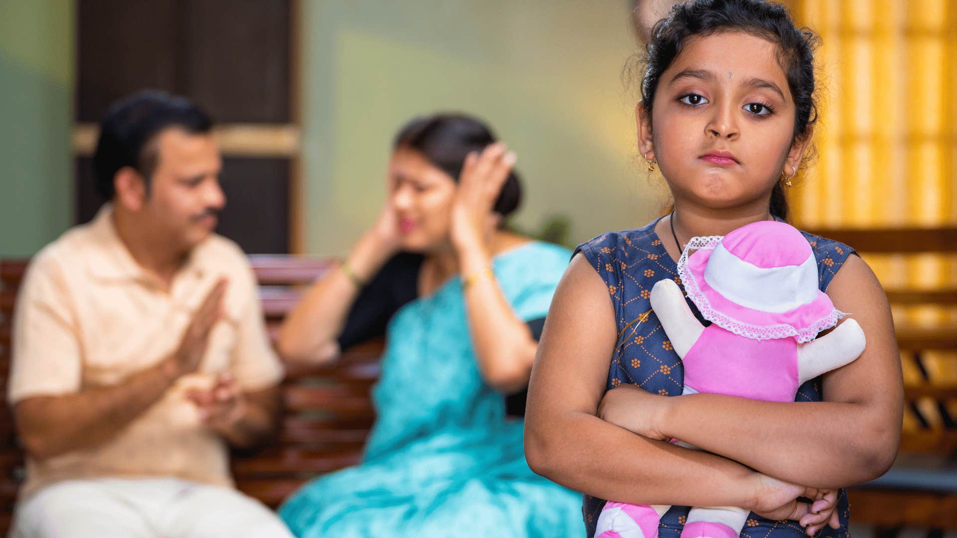 young girl looking stressed from chaotic parents arguing