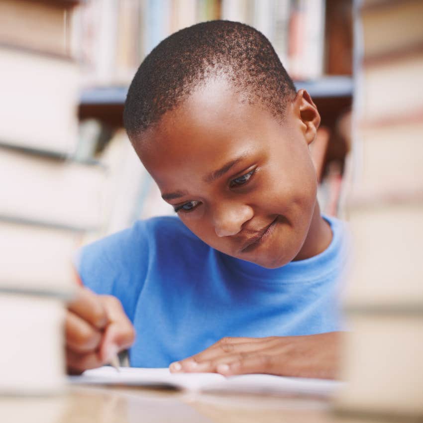 child thinking hard while writing at desk is distracted and struggling with reading and writing