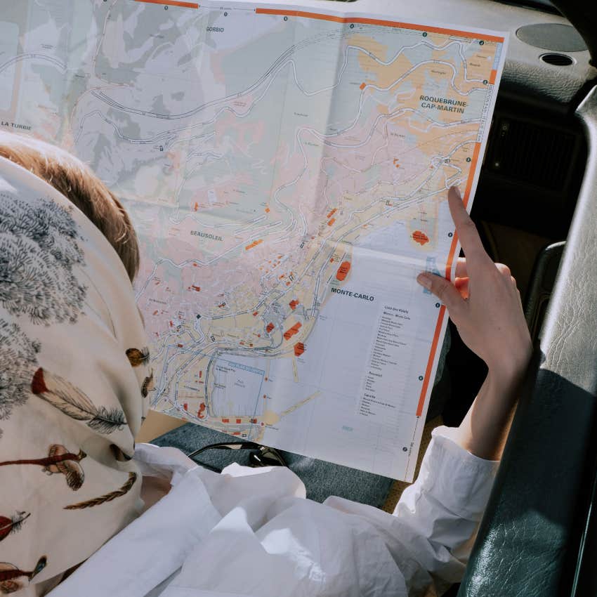 Woman looking at a paper map while in the car on a trip