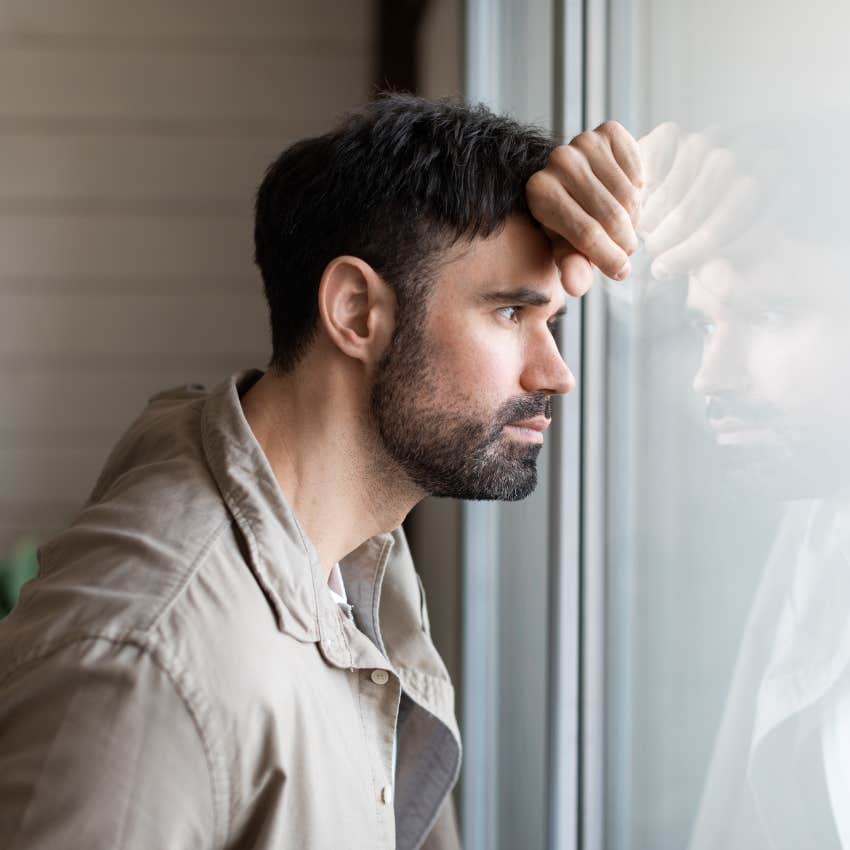 man self-reflecting while looking out window