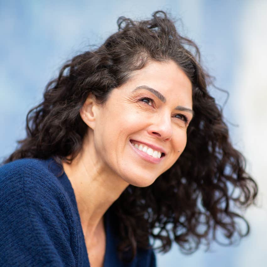 gen x woman smiling while thinking deeply