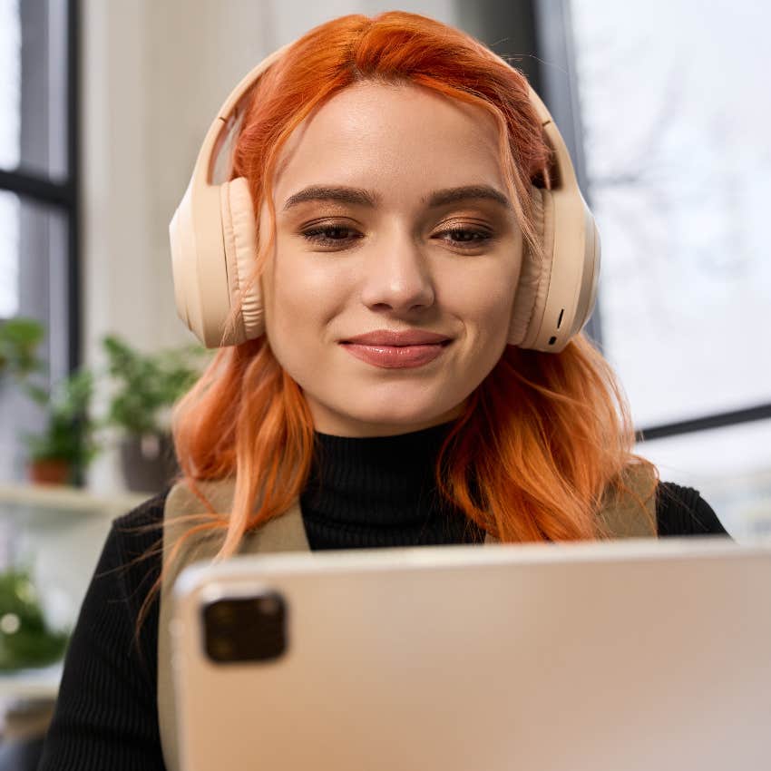 gen z woman working on laptop wearing headphones