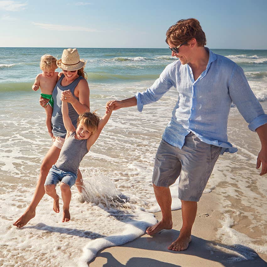 gen x couple playing with their children on beach