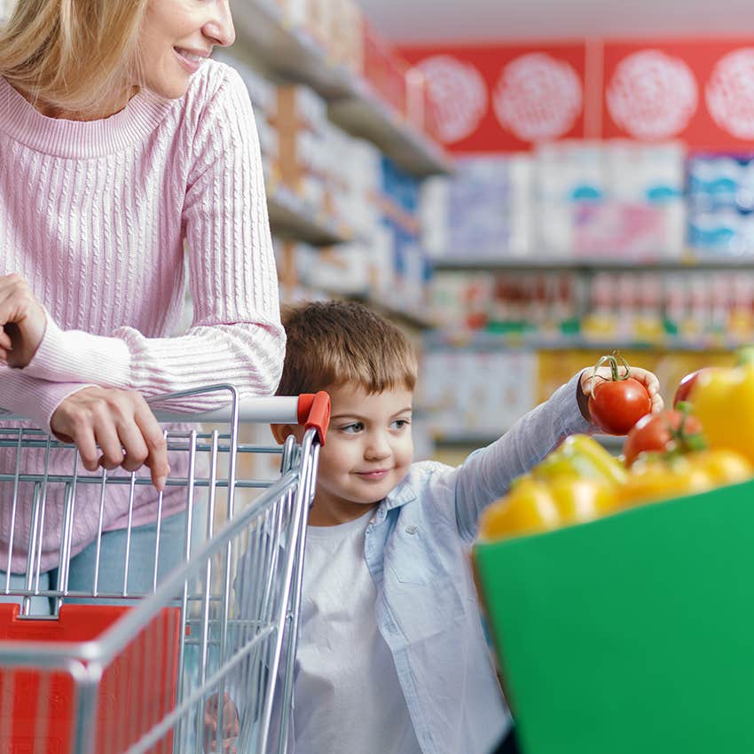 child holding up tomato in produce department