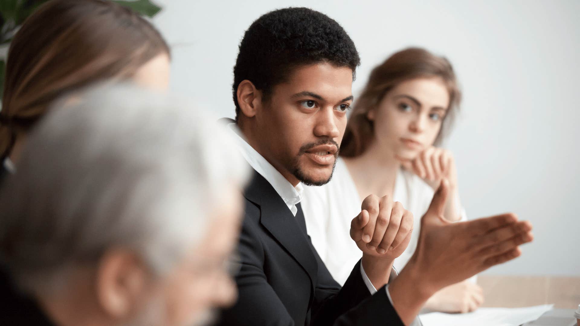 man cutting corners by delegating tasks to colleagues in work meeting