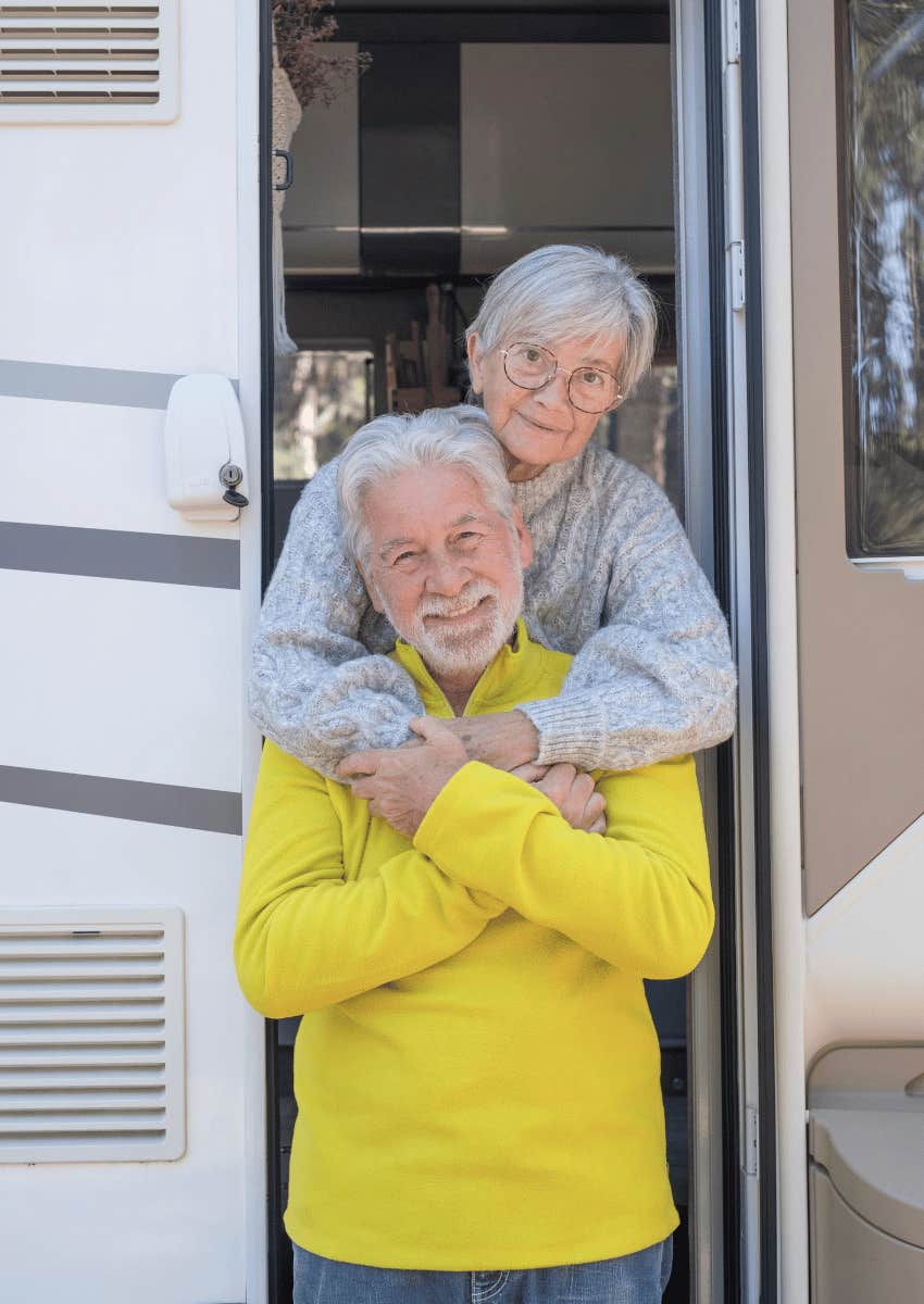 happy retired couple standing at RV door