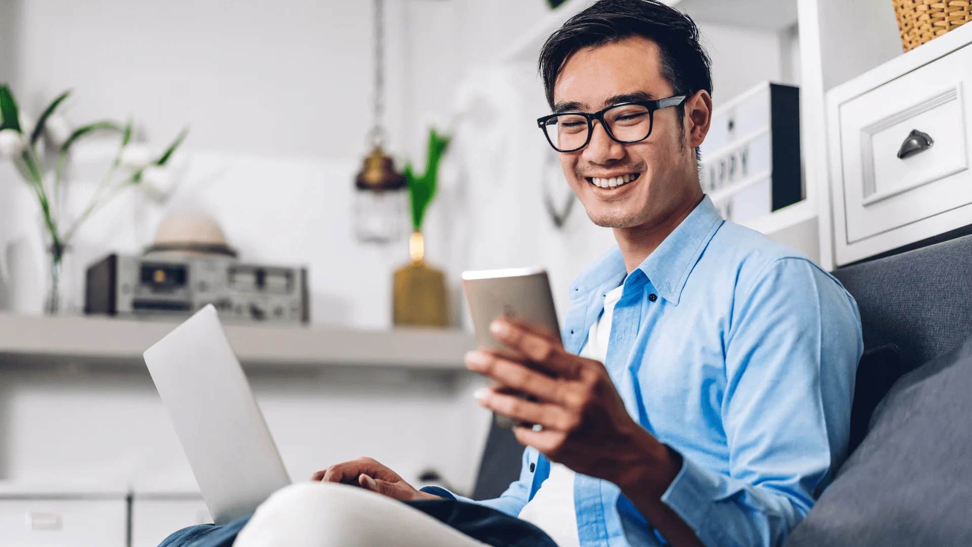 man on his phone smiling embracing solitude at home