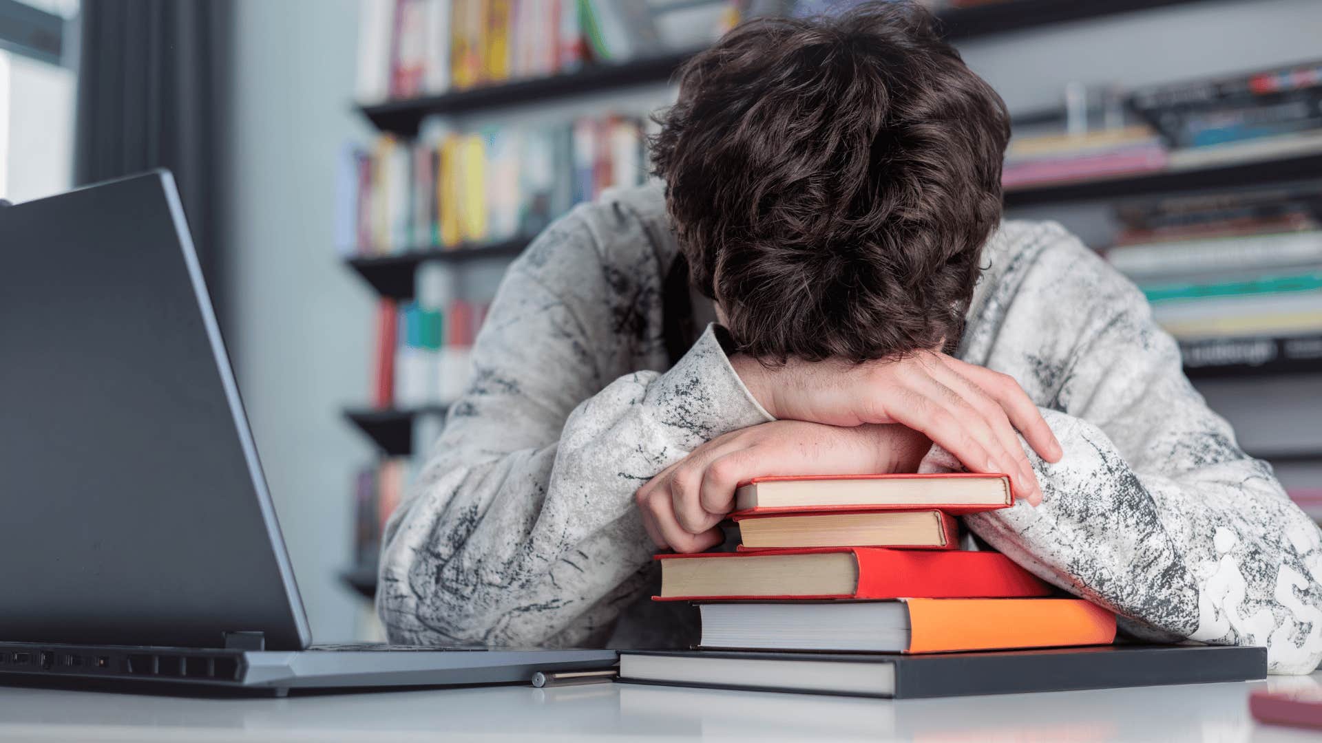 teen boy stressed out in the library not wanting to fail