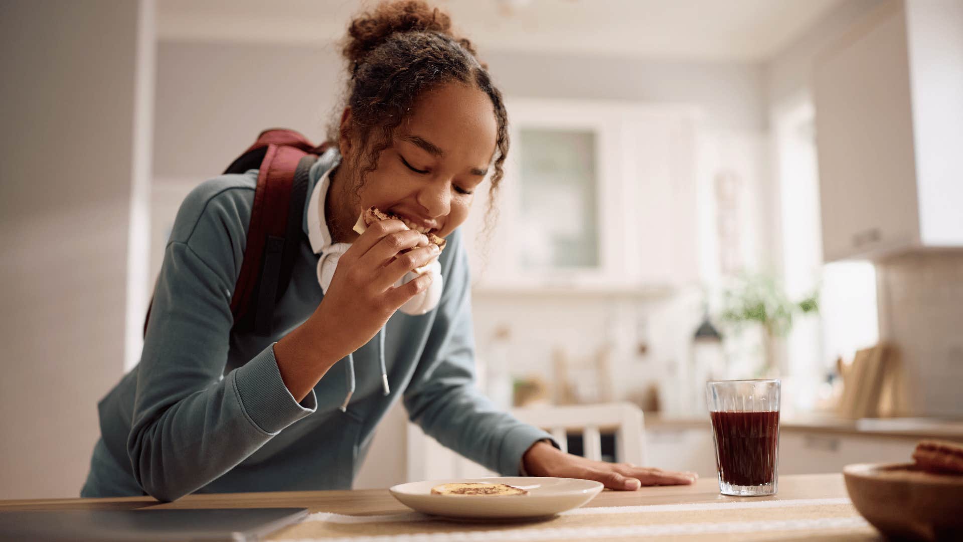 teenage girl finishing every bite on her plate eating a sandwich