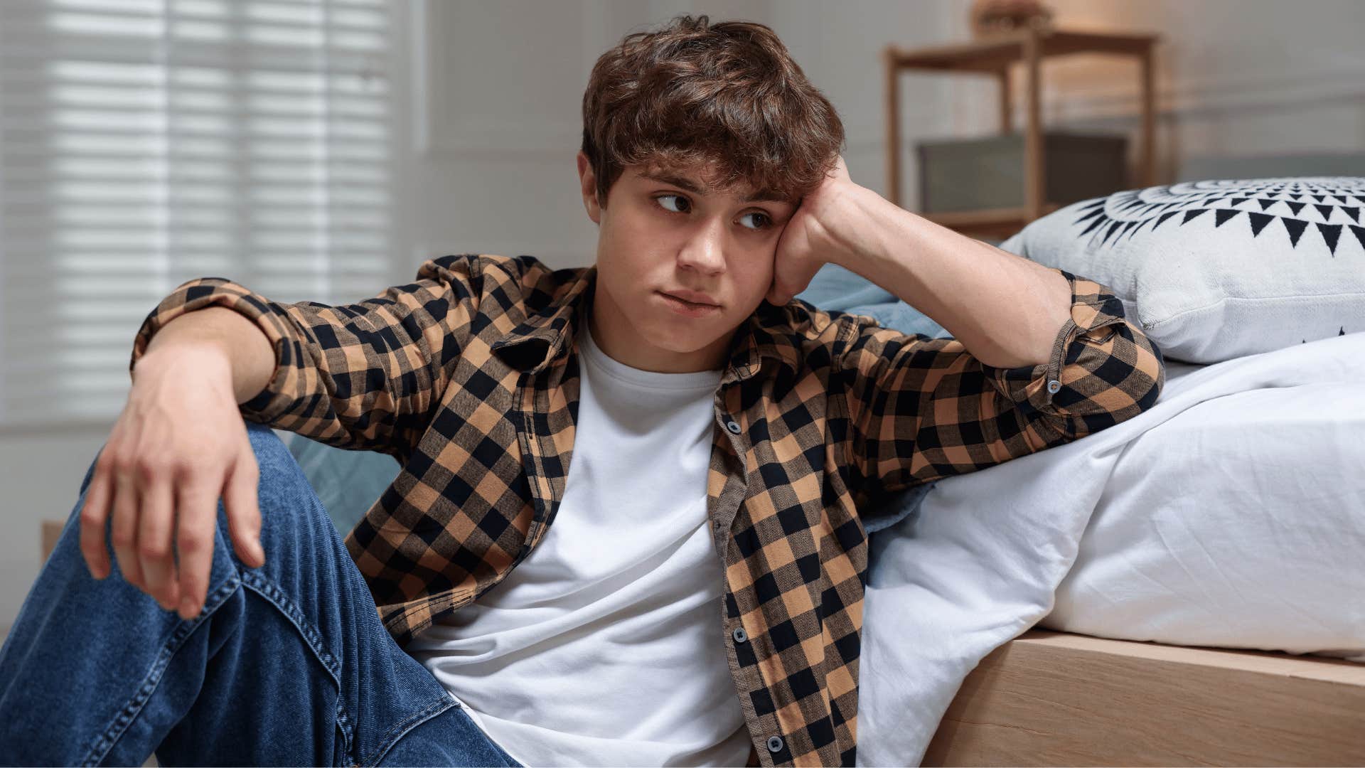 upset teenager sitting alone in his room refusing to follow rules