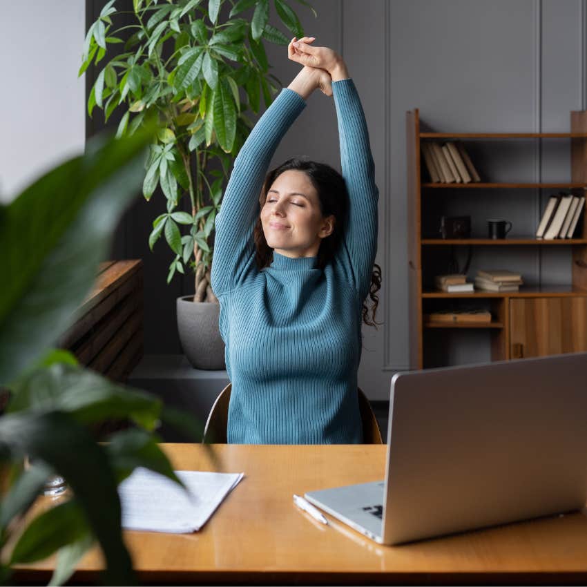woman stretching while sitting down working at desk