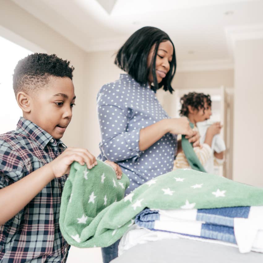 young boy helping his mom with household chores by folding laundry