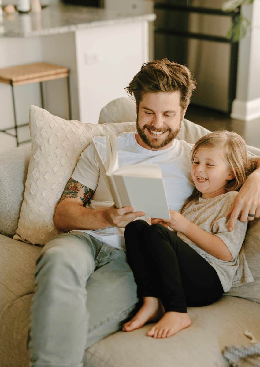 man reading with young girl on couch