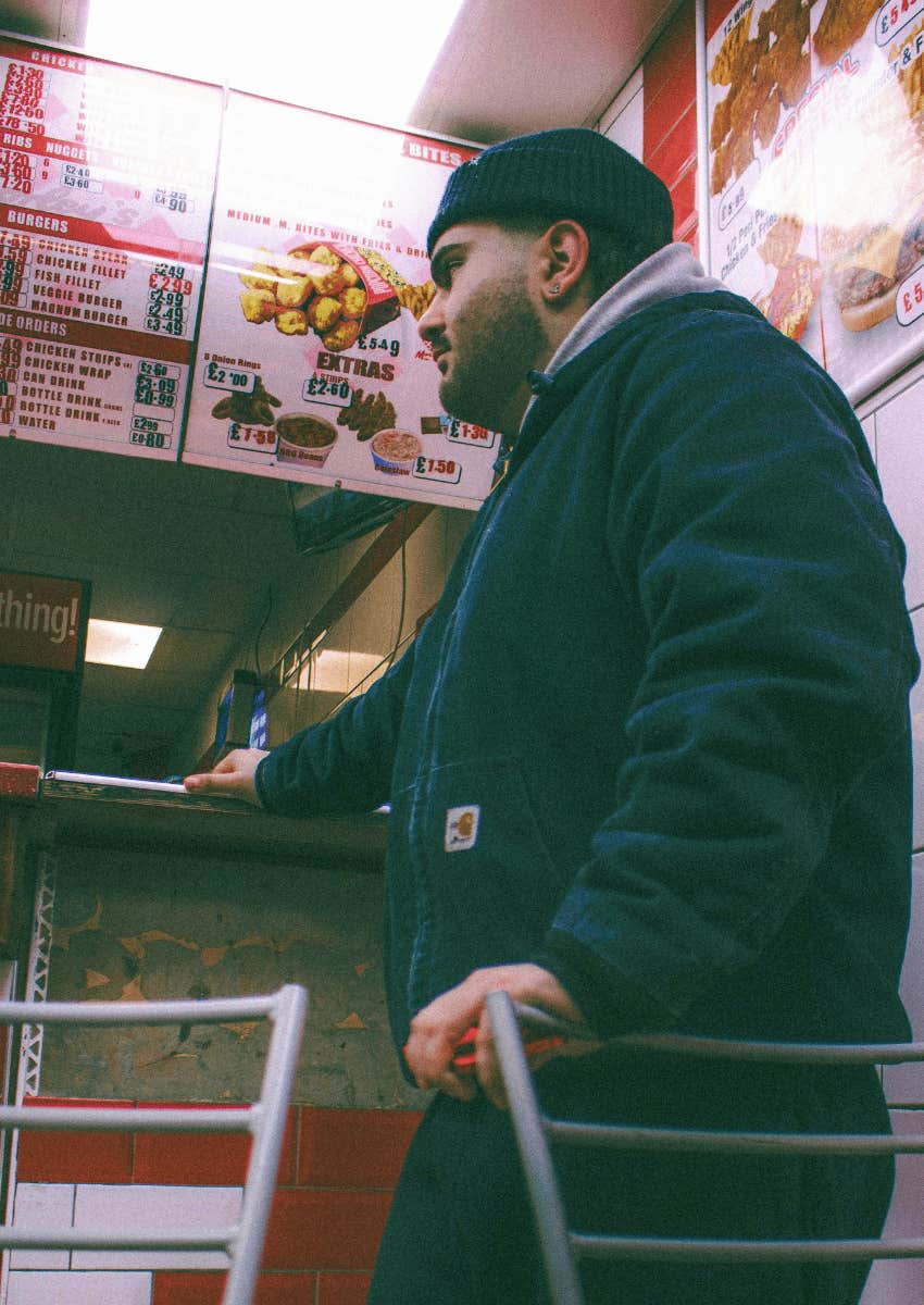 man standing in front of a fast food menu