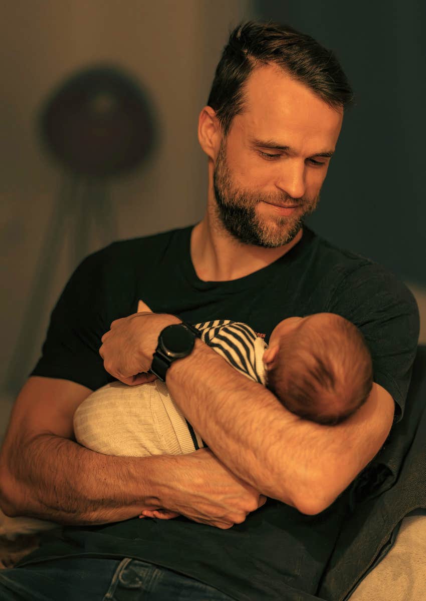 millennial dad holding a newborn baby
