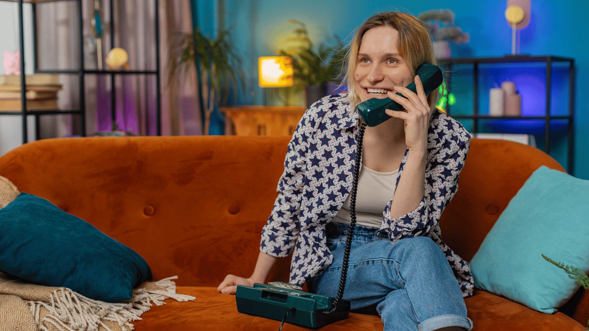 woman smiling on couch as she is chatting on landlines