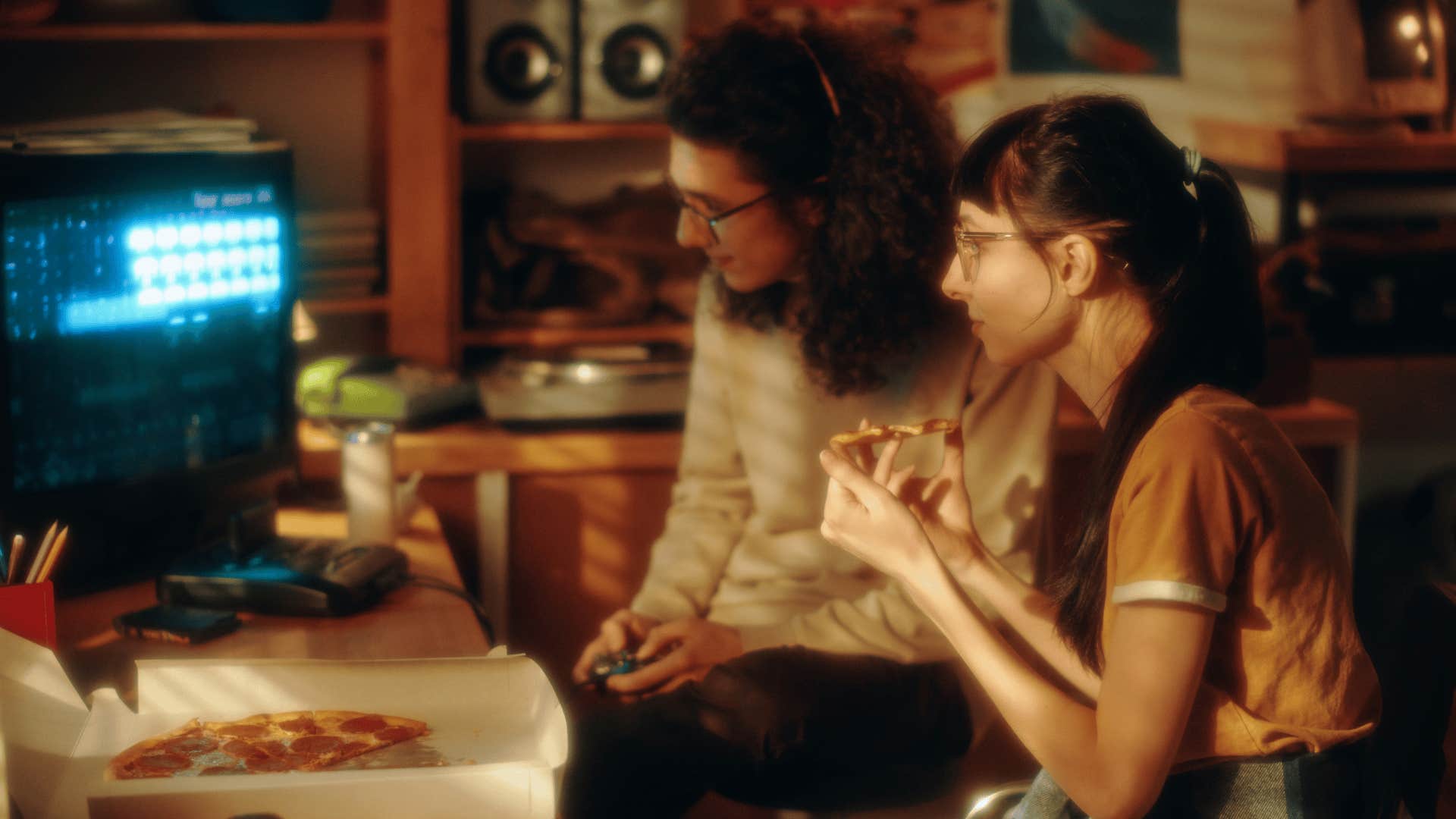 friends eating pizza as they play computer games