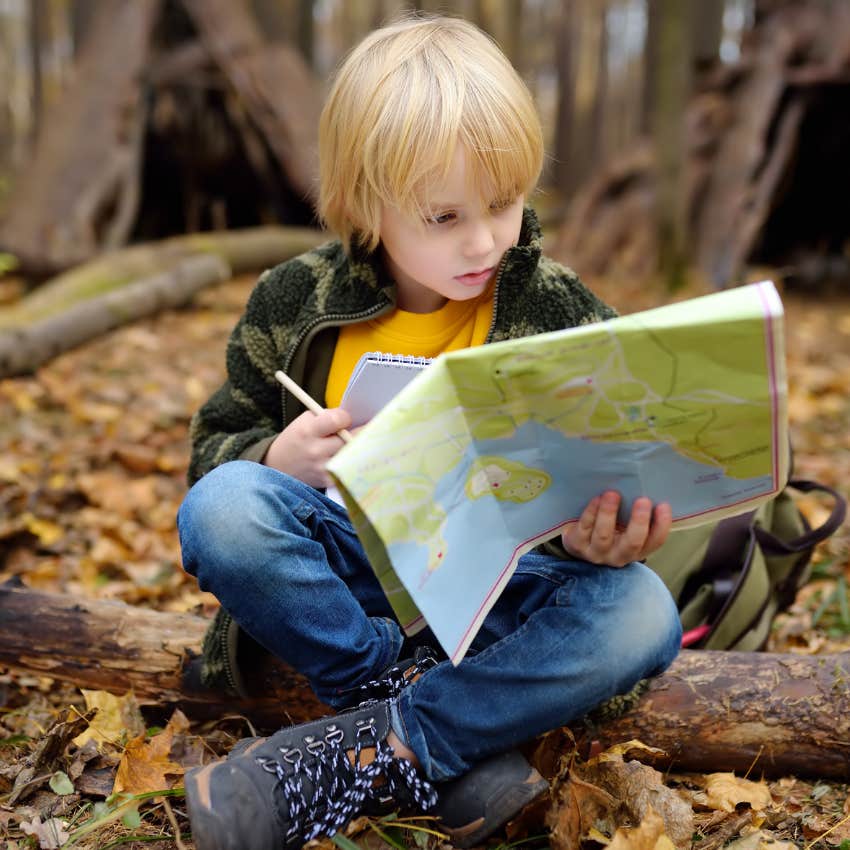 Little boy on a treasure hunt outside in the woods