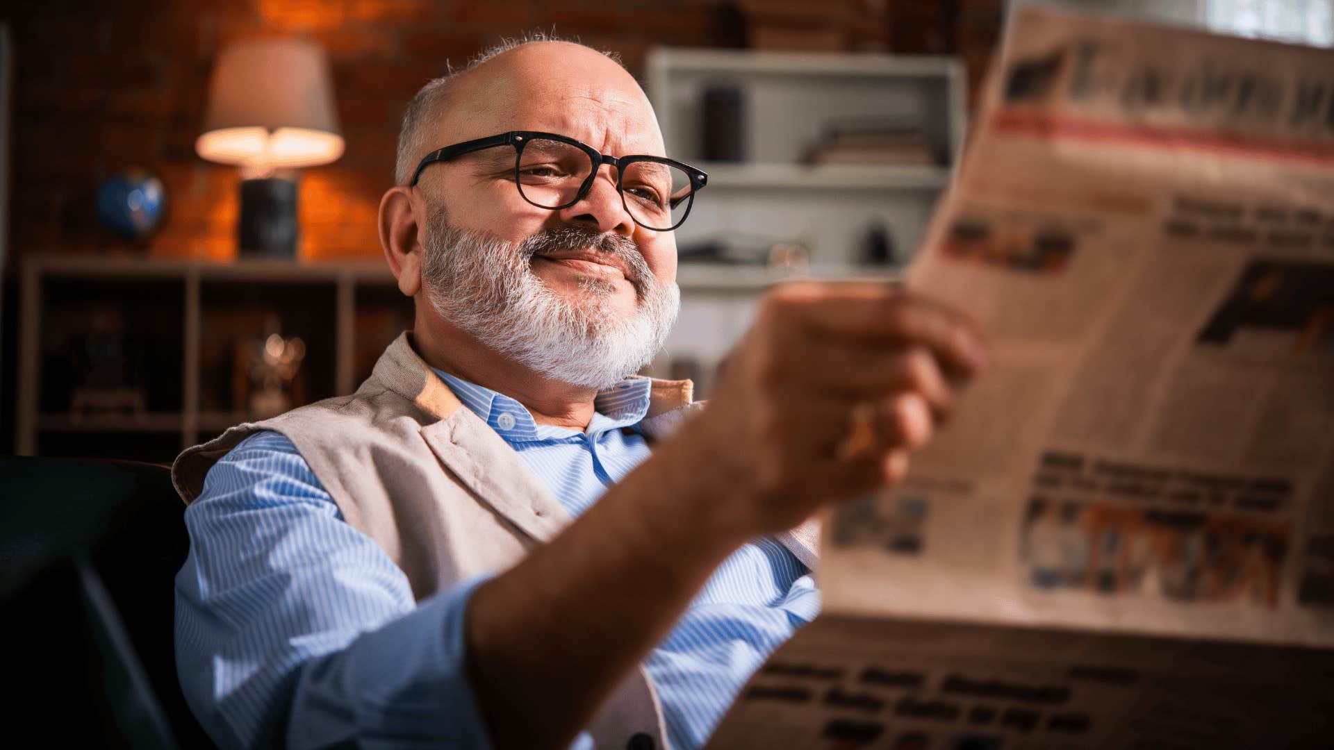 happy old man reading newspapers at home