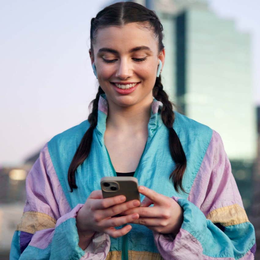 woman with an upturned collar smiling at her phone