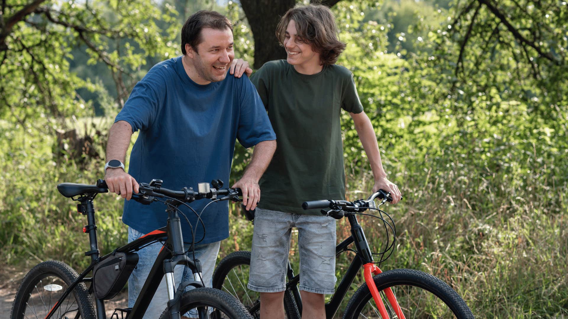 son and father riding bikes together happily