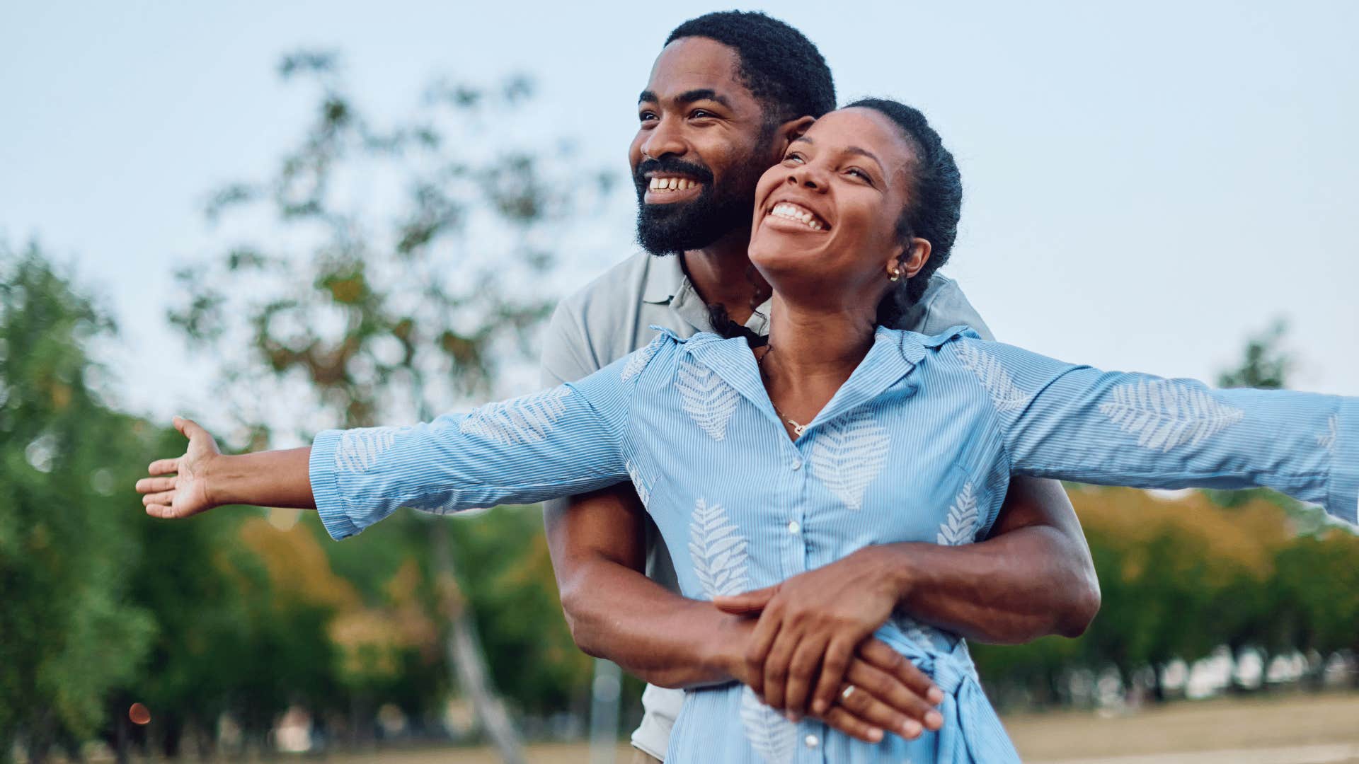 man hugging woman from behind being protective