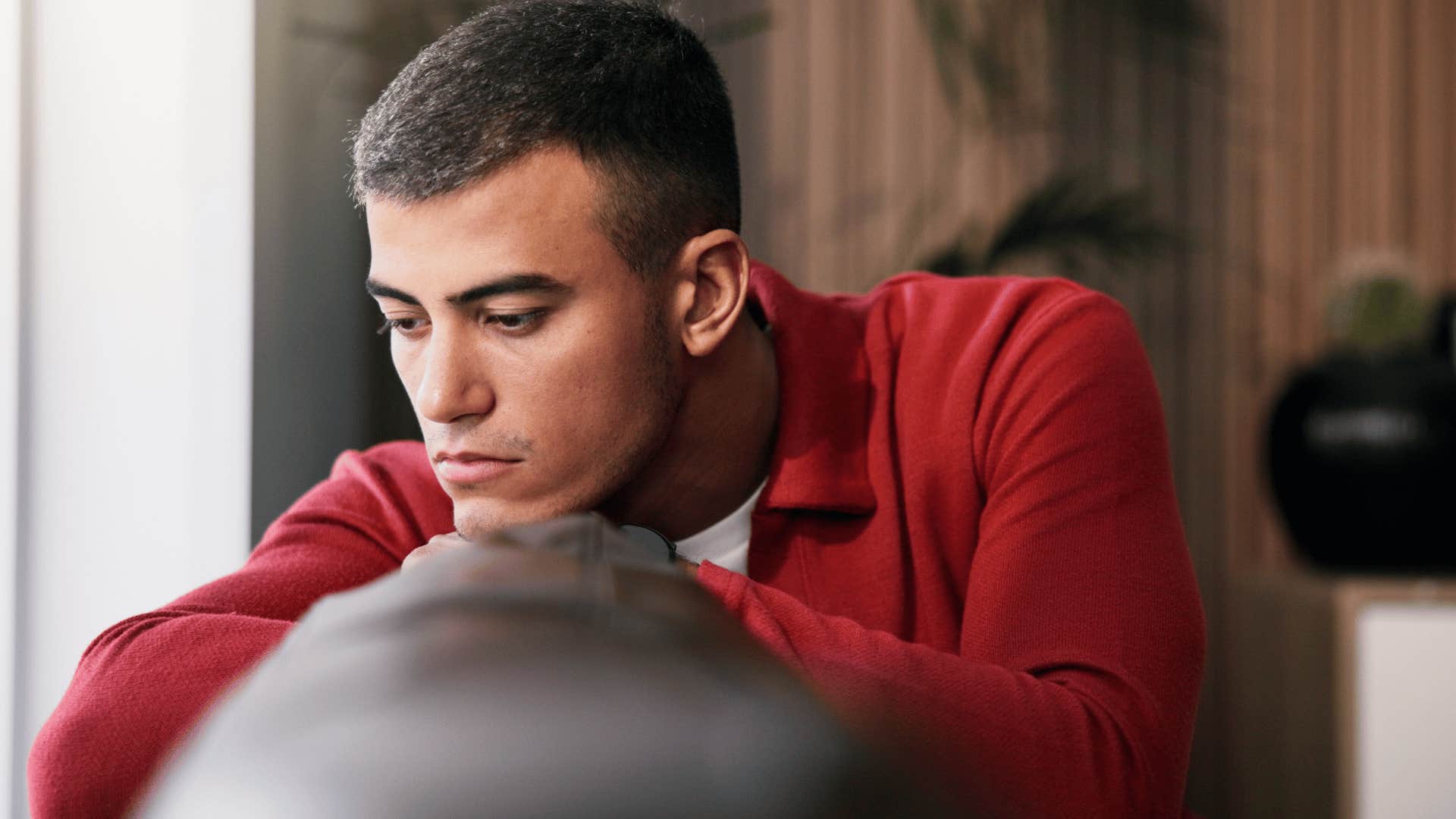 man in red shirt upset on couch thinking i'm just tired of everything