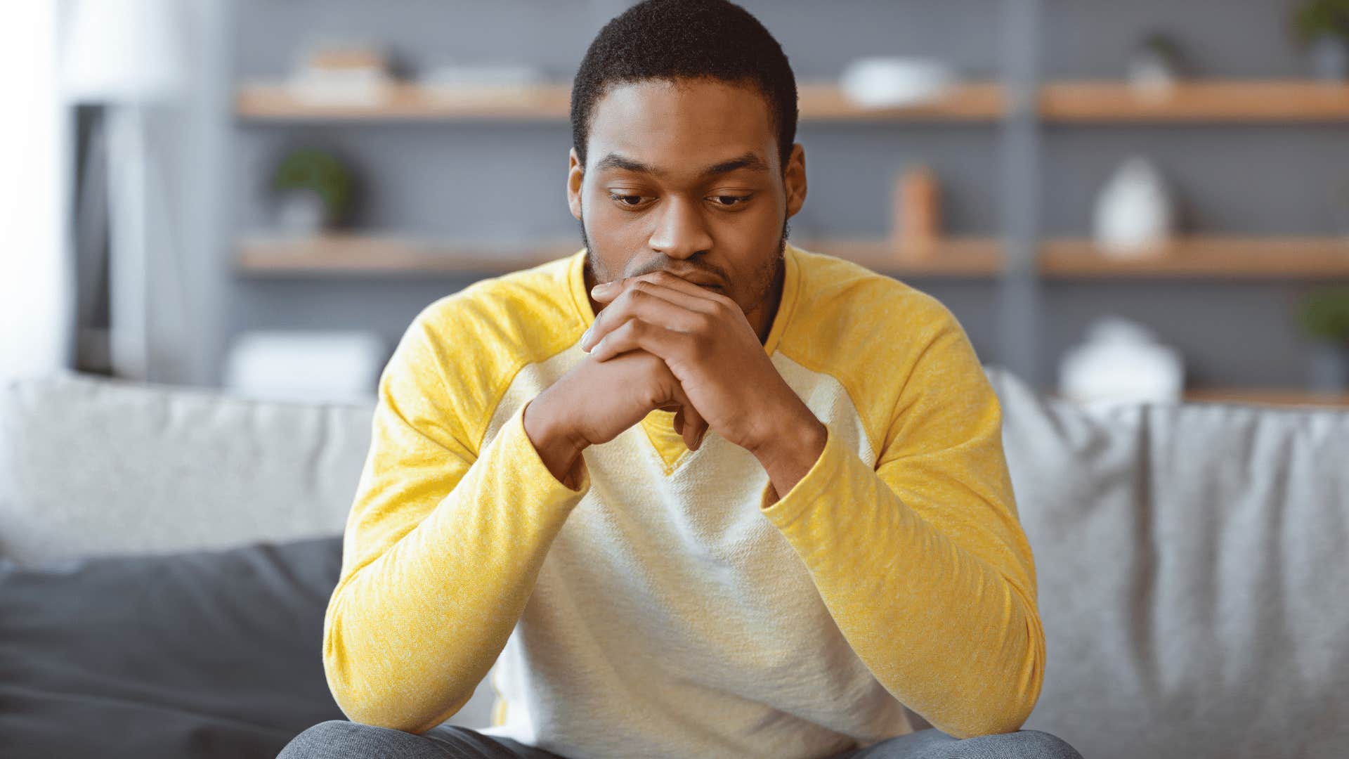 man in yellow shirt on couch thinking i always mess things up as he looks upset