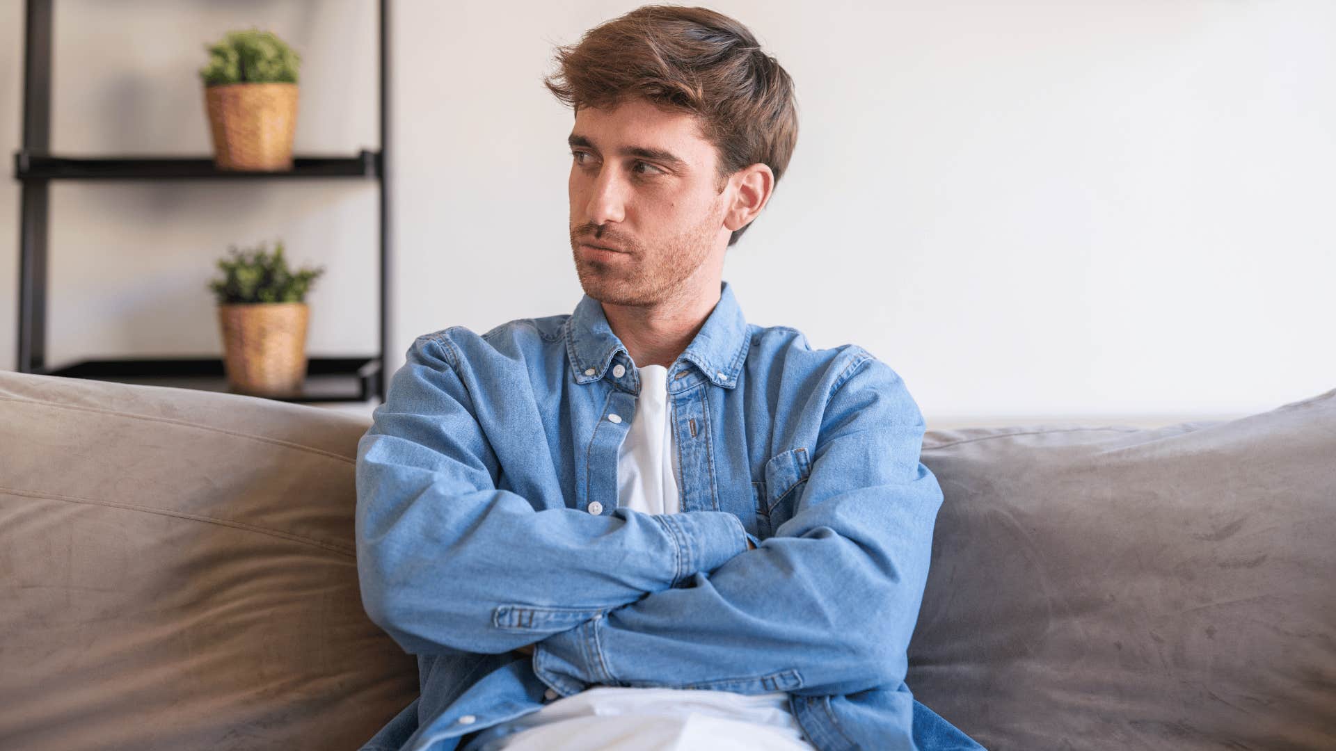 man in white and blue shirt crossing arms as he thinks nobody cares