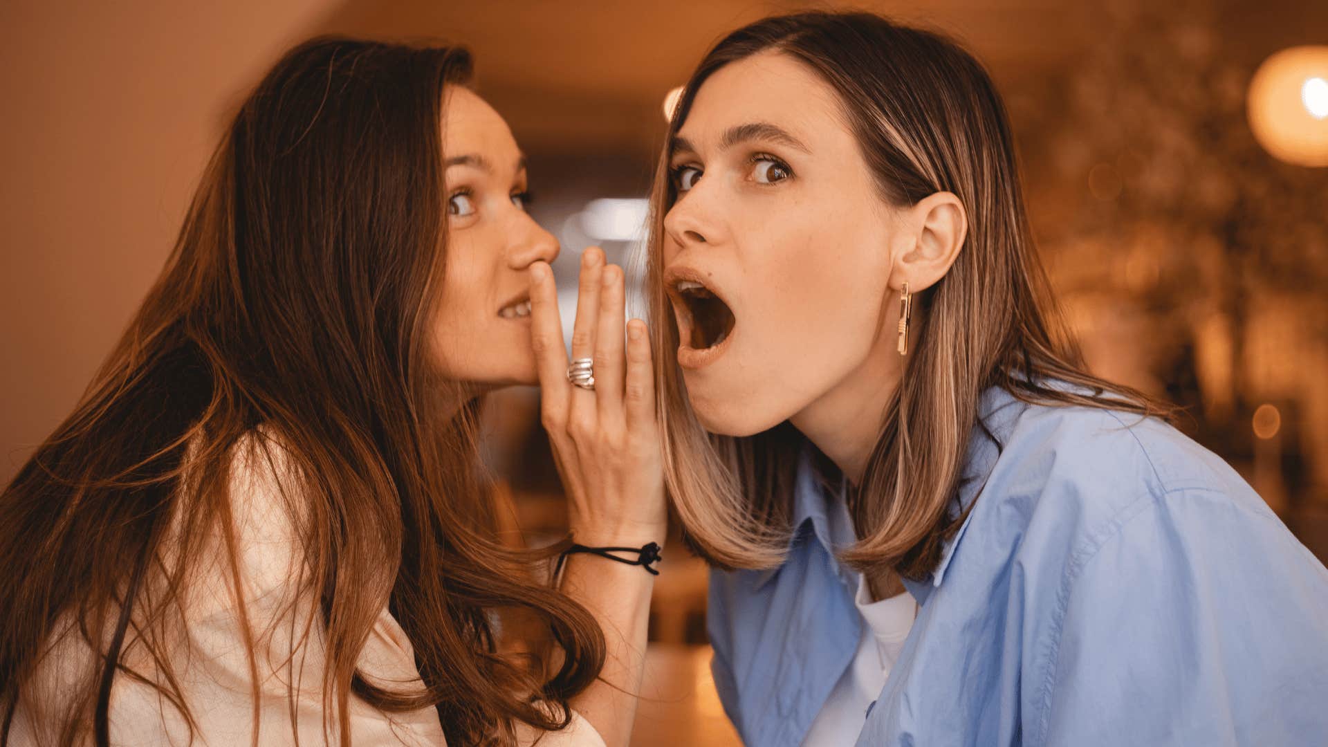 women gossiping in friend's ear saying you would not believe what happened