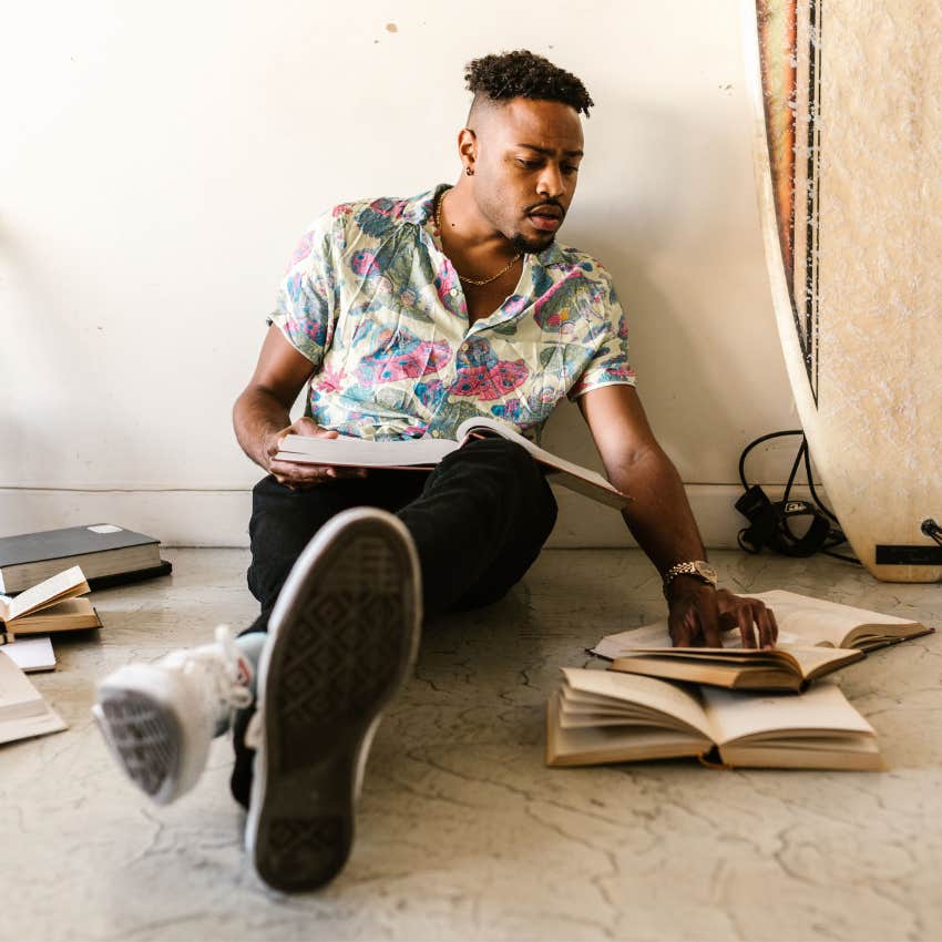 Man surrounded by books, hobbies, and creative projects that reflect diverse interests