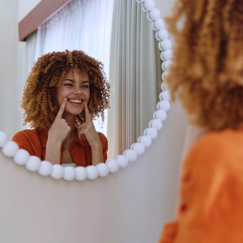 happy woman looking in the mirror not constantly comparing herself