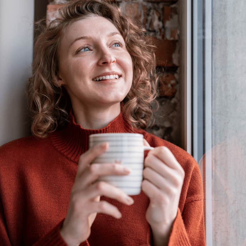 intentional and thoughtful woman drinking coffee watching the rain