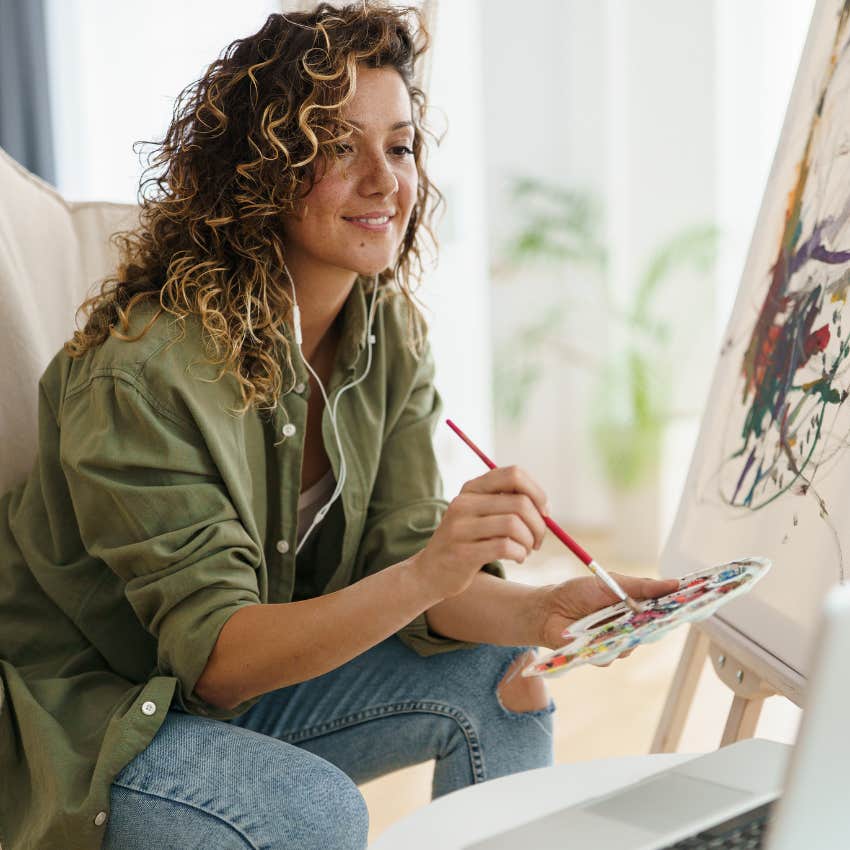 middle aged woman being creative painting at home