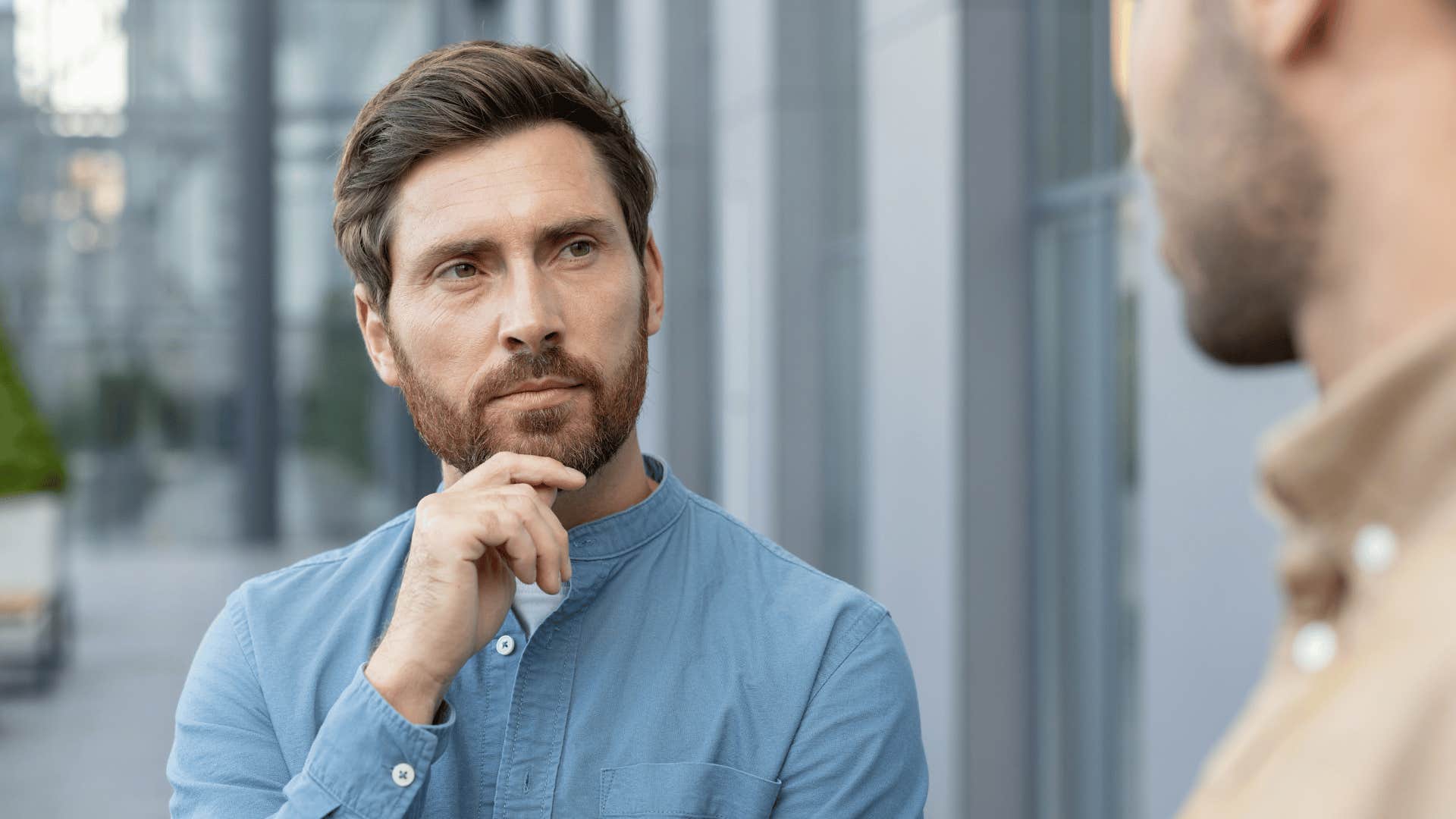 man listening to irritating man at work say work hard play hard