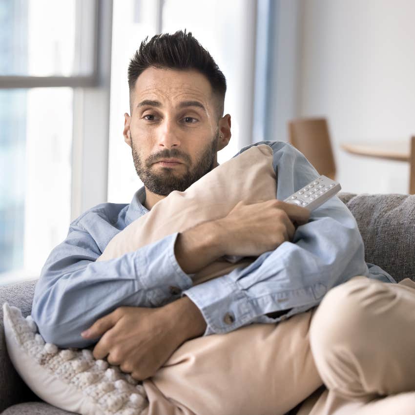 man hugging pillow watching horror movie